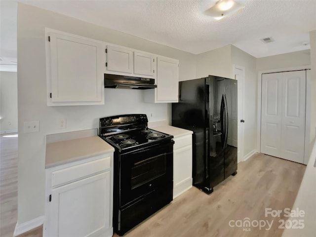 kitchen with a textured ceiling, black appliances, light hardwood / wood-style floors, and white cabinets