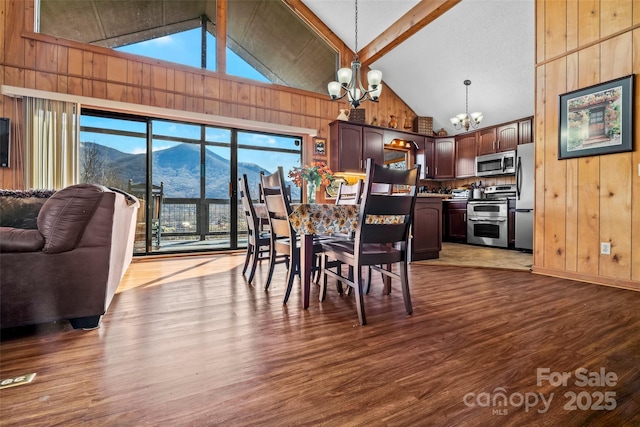 dining area with a chandelier, a healthy amount of sunlight, a mountain view, and wood walls