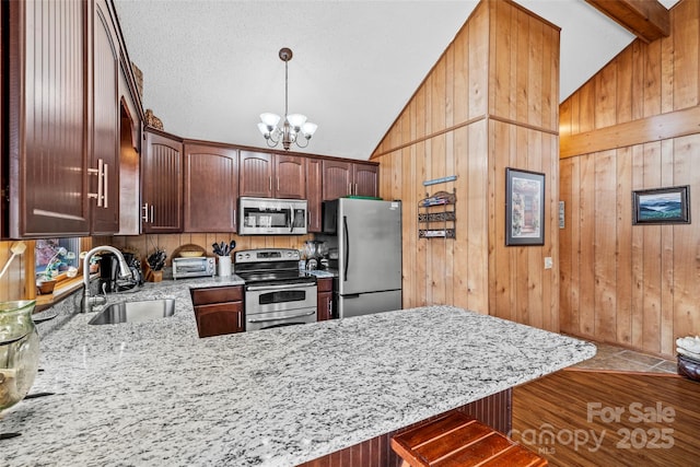 kitchen featuring stainless steel appliances, lofted ceiling, sink, and kitchen peninsula