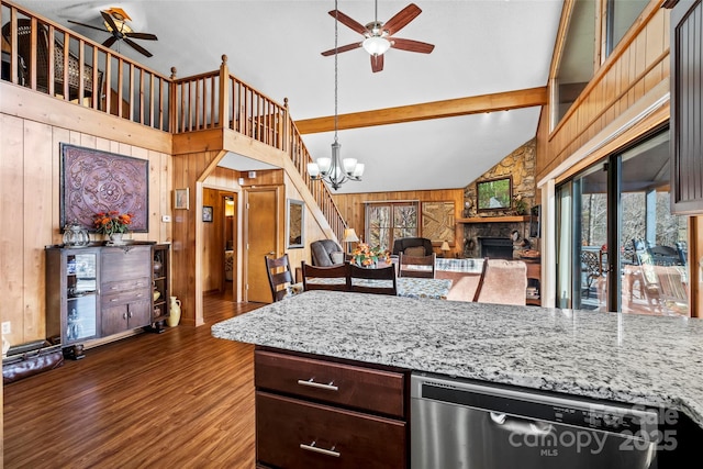 kitchen with beam ceiling, wood walls, stainless steel dishwasher, dark hardwood / wood-style flooring, and a fireplace