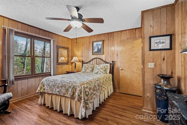 bedroom featuring hardwood / wood-style floors, wooden walls, and a textured ceiling