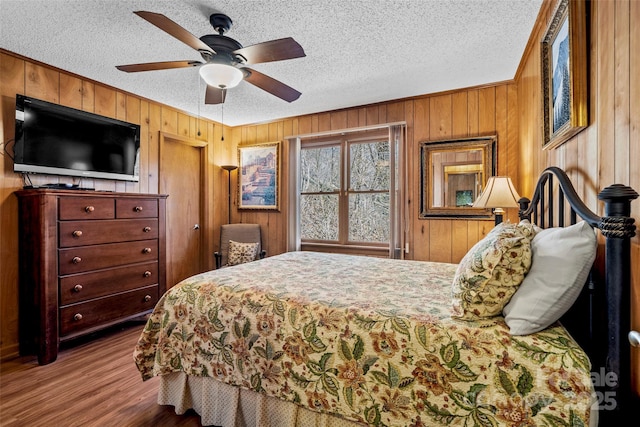 bedroom featuring hardwood / wood-style floors, a textured ceiling, and wood walls