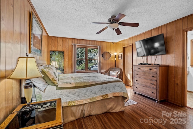 bedroom with dark wood-type flooring, ceiling fan, a textured ceiling, and wood walls