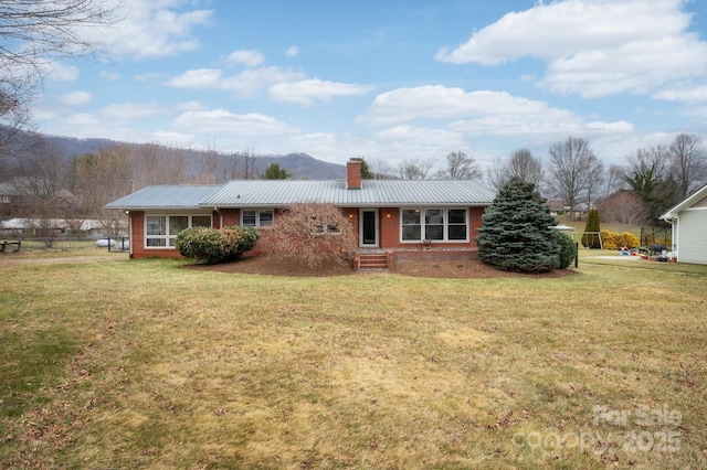 ranch-style home with metal roof, a chimney, a front lawn, and brick siding