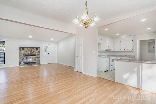 kitchen featuring white cabinetry, decorative light fixtures, white range with electric cooktop, a fireplace, and light hardwood / wood-style floors