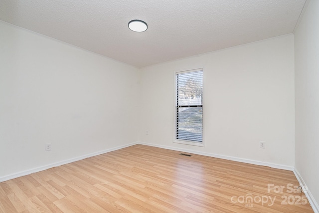 spare room featuring ornamental molding, a textured ceiling, and light hardwood / wood-style flooring