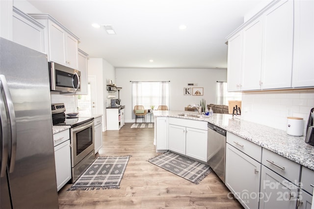 137 Tenth Green Ct, Statesville, NC 28677 - kitchen with appliances with stainless steel finishes, tasteful backsplash, a peninsula, light wood-type flooring, and recessed lighting