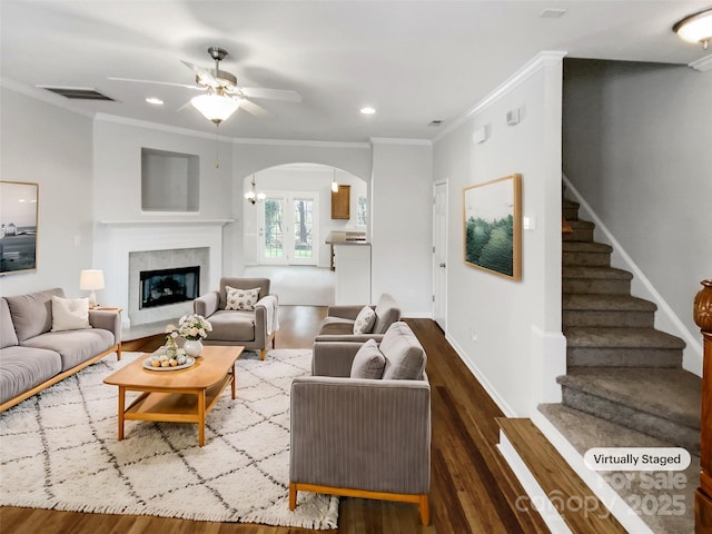 living room with crown molding, hardwood / wood-style flooring, ceiling fan, and a tiled fireplace