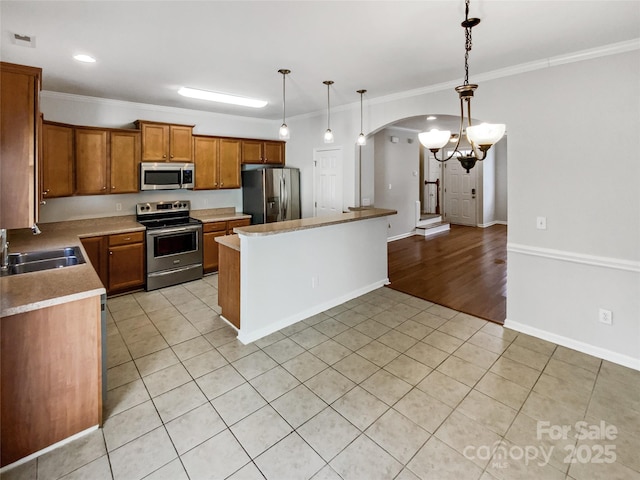 kitchen featuring light tile patterned flooring, stainless steel appliances, ornamental molding, and decorative light fixtures