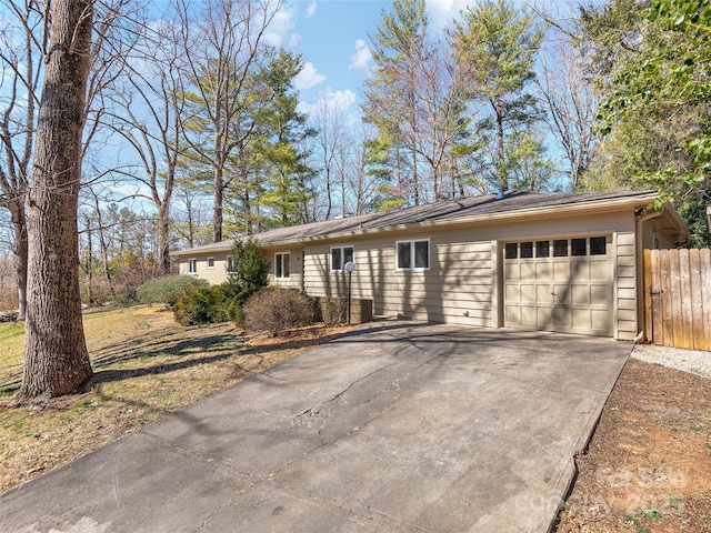 single story home with a garage, concrete driveway, and fence