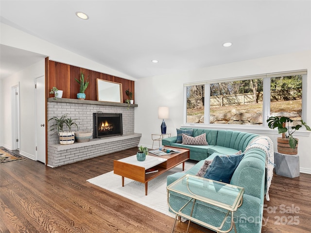 living area with lofted ceiling, a brick fireplace, wood finished floors, and recessed lighting