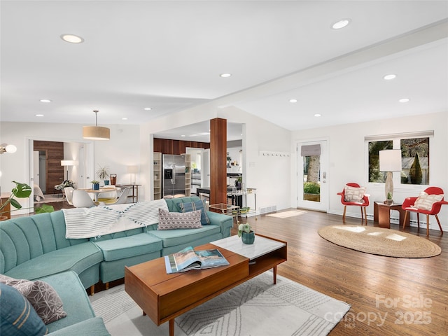 living room with vaulted ceiling with beams, recessed lighting, visible vents, light wood-style flooring, and baseboards