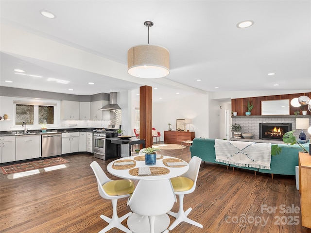 dining area with a fireplace, dark wood-style flooring, and recessed lighting