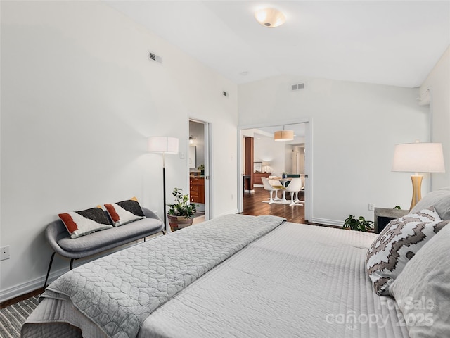 bedroom featuring lofted ceiling, visible vents, baseboards, and wood finished floors