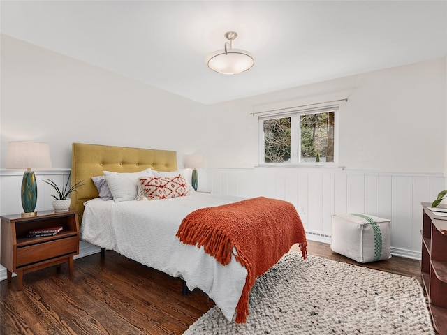 bedroom featuring wood finished floors and wainscoting