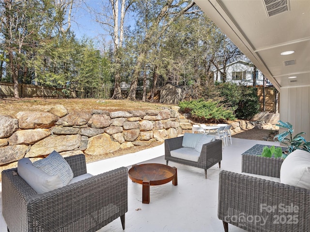 view of patio / terrace with visible vents, outdoor lounge area, a storage shed, fence, and an outdoor structure