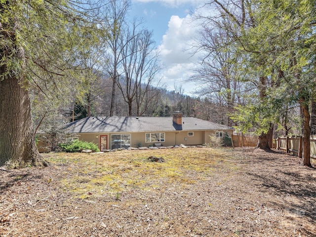 rear view of property featuring a chimney and fence