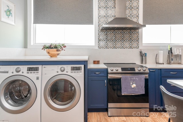 laundry room with separate washer and dryer and light hardwood / wood-style floors