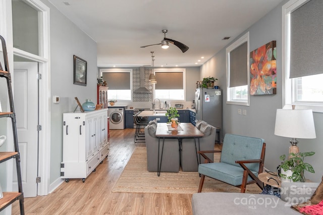 kitchen featuring a wealth of natural light, washer / dryer, a kitchen breakfast bar, stainless steel appliances, and wall chimney exhaust hood