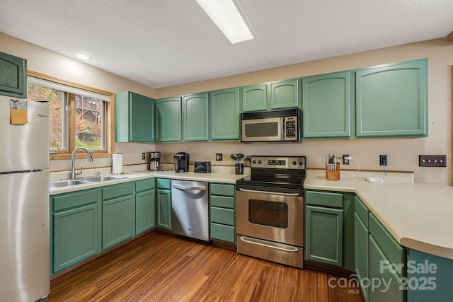 kitchen with green cabinets, stainless steel appliances, a sink, and light countertops