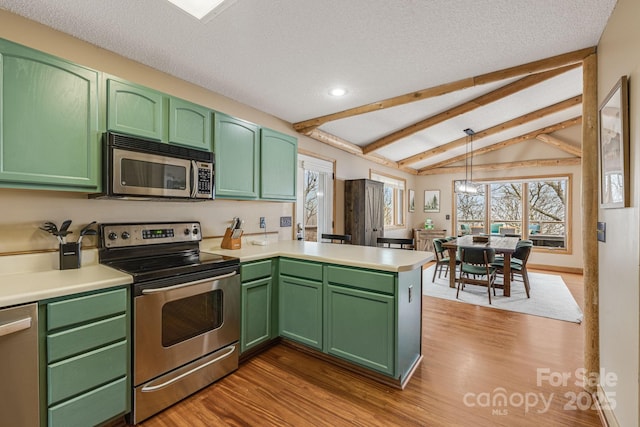 kitchen with appliances with stainless steel finishes, vaulted ceiling with beams, a peninsula, light countertops, and green cabinets