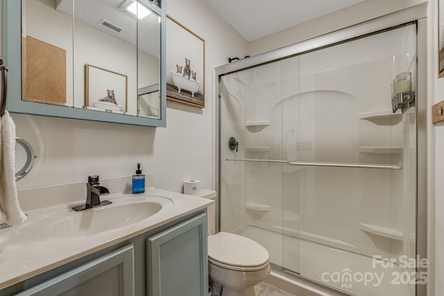 bathroom featuring toilet, a stall shower, vanity, and visible vents