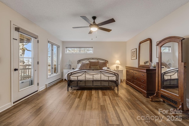 bedroom with access to exterior, multiple windows, baseboard heating, and wood finished floors