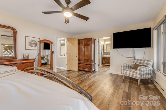 bedroom with a baseboard heating unit, connected bathroom, ceiling fan, wood finished floors, and baseboards