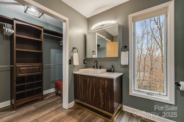 bathroom featuring baseboards, vanity, a textured ceiling, and wood finished floors