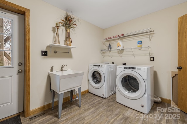 laundry room featuring laundry area, baseboards, visible vents, washer and clothes dryer, and wood finished floors