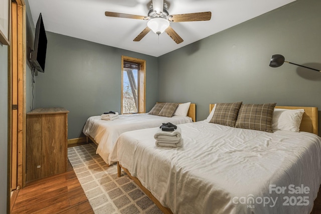 bedroom featuring dark wood-style floors, ceiling fan, and baseboards