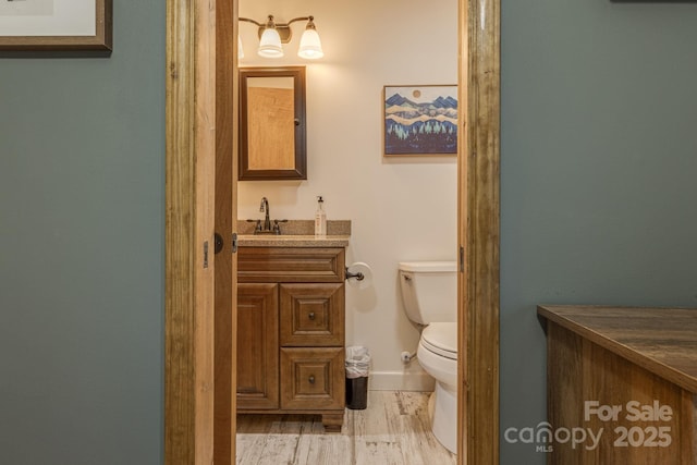 bathroom with baseboards, vanity, toilet, and wood finished floors