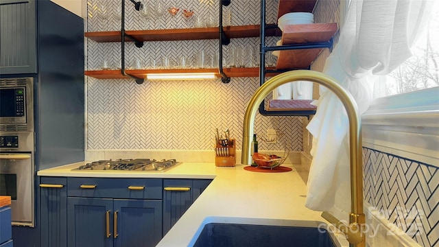 kitchen featuring appliances with stainless steel finishes, blue cabinetry, and backsplash