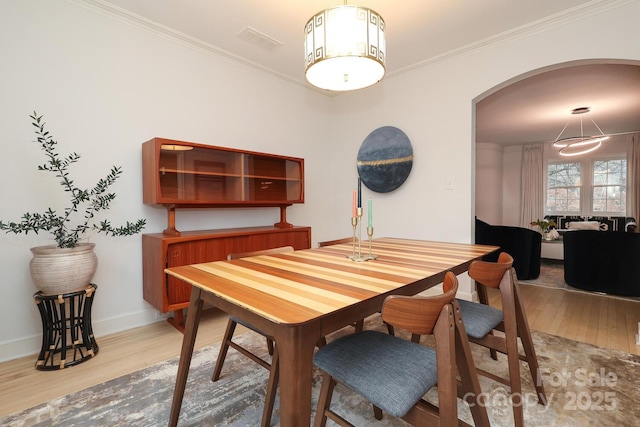 dining room with ornamental molding and light hardwood / wood-style floors