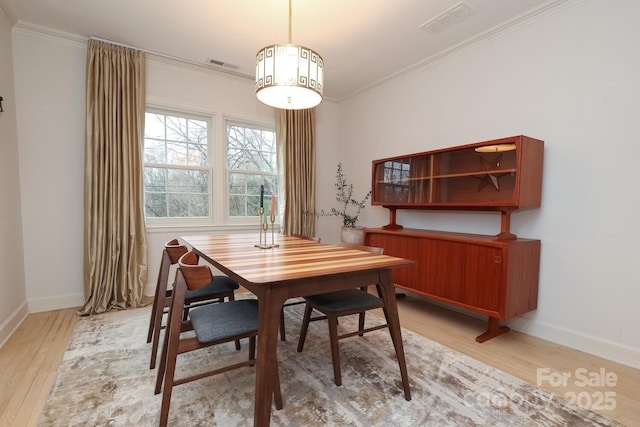 dining room with crown molding and light hardwood / wood-style flooring