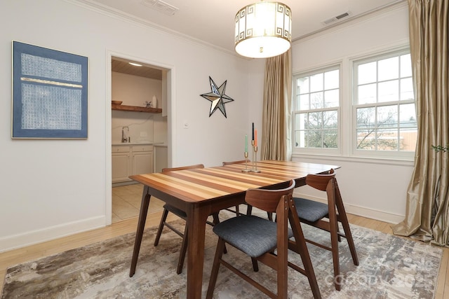 dining space featuring ornamental molding and light hardwood / wood-style floors