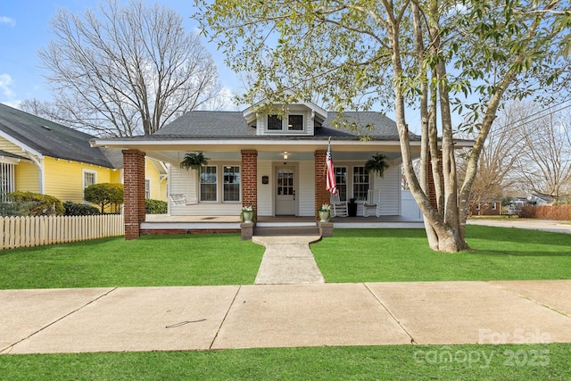 bungalow-style home featuring covered porch, fence, and a front yard