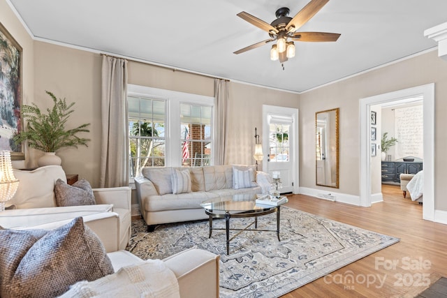 living room with ceiling fan, crown molding, baseboards, and wood finished floors