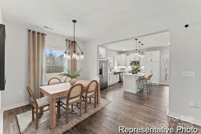 dining room featuring sink, dark wood-type flooring, and a chandelier