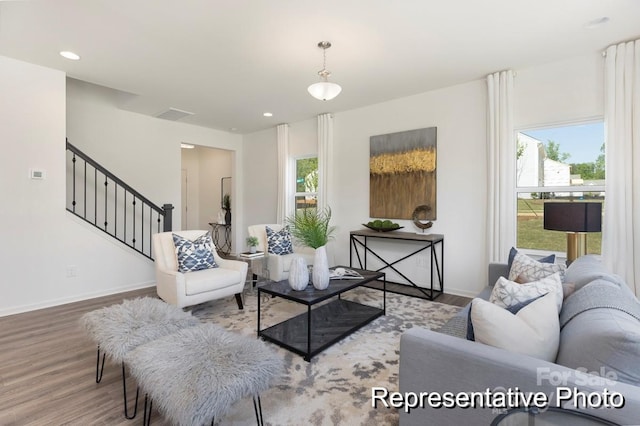 living area featuring baseboards, plenty of natural light, wood finished floors, and stairway