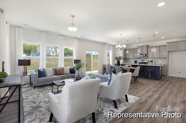 living area with recessed lighting, a notable chandelier, a wealth of natural light, and light wood-type flooring