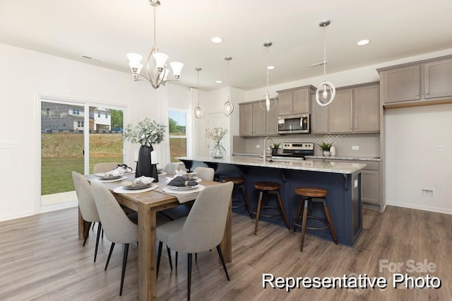 dining room with visible vents, wood finished floors, baseboards, a notable chandelier, and recessed lighting