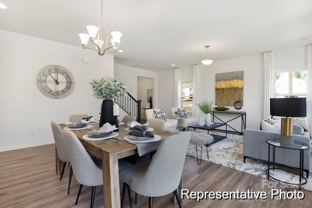 dining space featuring baseboards, stairs, wood finished floors, and an inviting chandelier