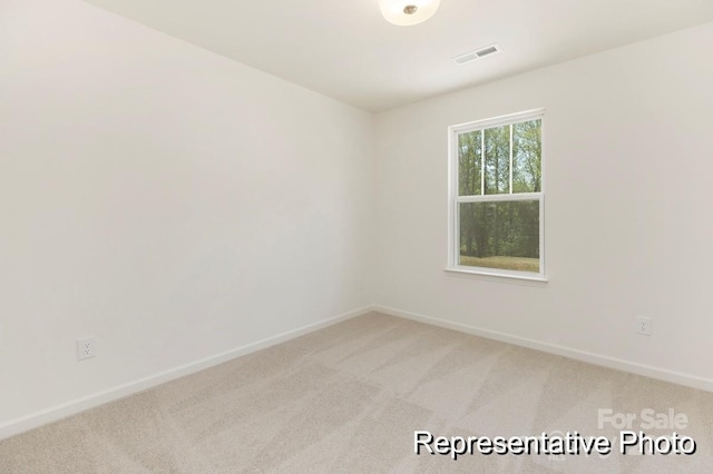 empty room with baseboards, visible vents, and light carpet