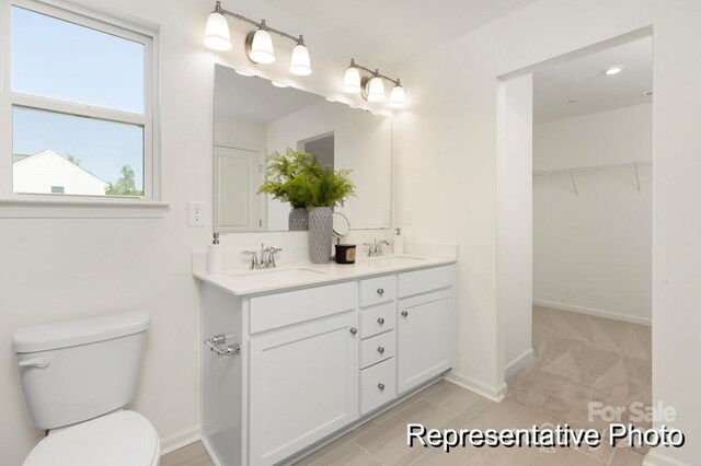 full bath with a sink, baseboards, toilet, and double vanity