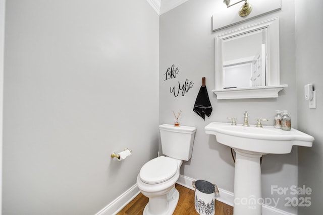 half bath with toilet, baseboards, and wood finished floors