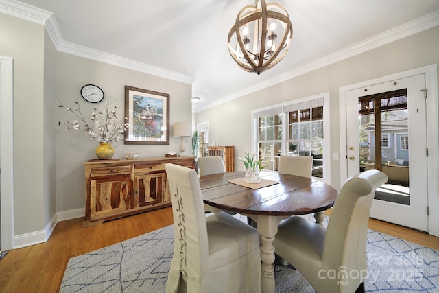 dining area with light wood-style floors, crown molding, baseboards, and an inviting chandelier