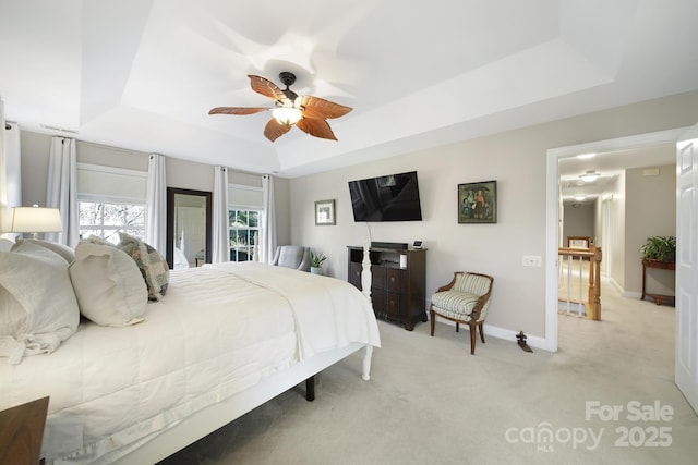 bedroom with a ceiling fan, a raised ceiling, light carpet, and baseboards