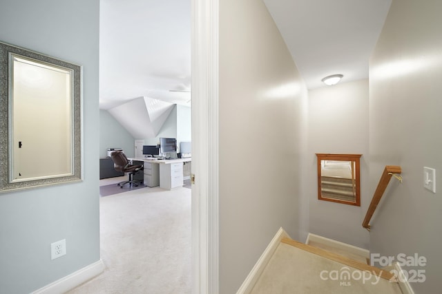 hallway with lofted ceiling, baseboards, and carpet flooring