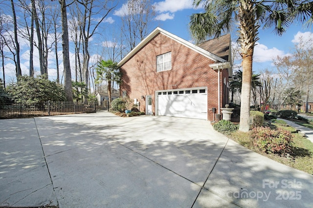 view of side of home with driveway, an attached garage, fence, and brick siding